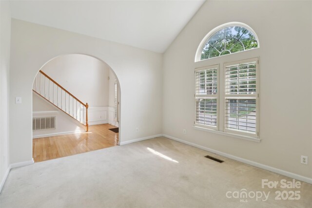2321 Oberwood Dr, Charlotte, NC 28270 - empty room featuring carpet flooring, arched walkways, stairway, and high vaulted ceiling