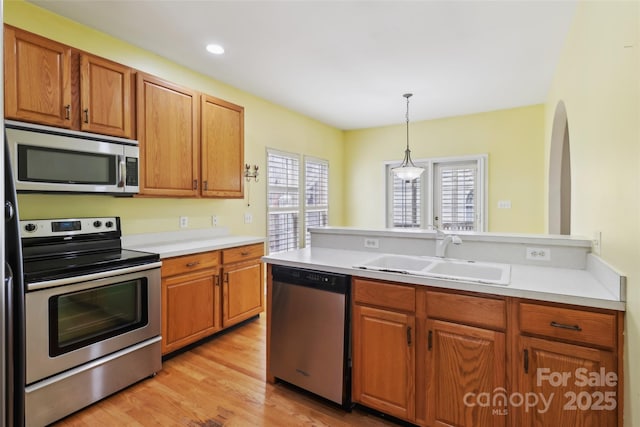 2321 Oberwood Dr, Charlotte, NC 28270 - kitchen featuring stainless steel appliances, light countertops, pendant lighting, light wood-style flooring, and brown cabinetry