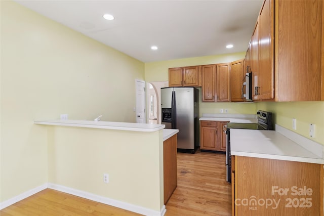 2321 Oberwood Dr, Charlotte, NC 28270 - kitchen featuring appliances with stainless steel finishes, brown cabinetry, light wood finished floors, light countertops, and a peninsula