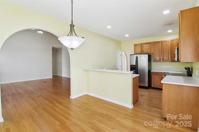 2321 Oberwood Dr, Charlotte, NC 28270 - kitchen featuring arched walkways, stainless steel refrigerator with ice dispenser, stove, brown cabinetry, and light wood-style flooring