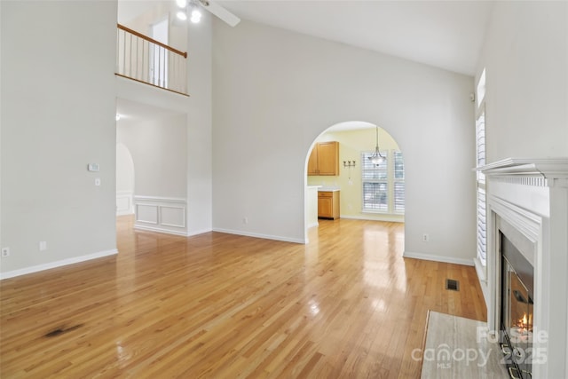 2321 Oberwood Dr, Charlotte, NC 28270 - unfurnished living room featuring arched walkways, a fireplace with flush hearth, a ceiling fan, high vaulted ceiling, and light wood-type flooring