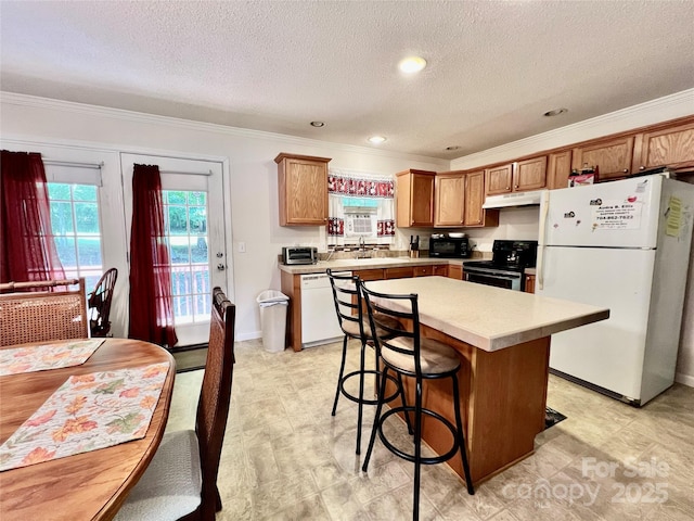 1031 Daniel Dr, Stanley, NC 28164 - kitchen featuring black appliances, under cabinet range hood, ornamental molding, light countertops, and a kitchen island