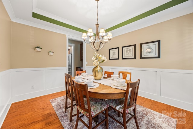 6422 Northern Red Oak Dr, Mint Hill, NC 28227 - dining room with a raised ceiling, a chandelier, ornamental molding, light wood finished floors, and a wainscoted wall