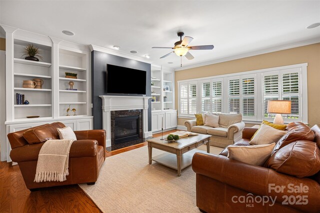 6422 Northern Red Oak Dr, Mint Hill, NC 28227 - living room with ceiling fan, wood finished floors, a premium fireplace, built in shelves, and crown molding