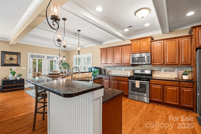 6422 Northern Red Oak Dr, Mint Hill, NC 28227 - kitchen with appliances with stainless steel finishes, light wood finished floors, beam ceiling, a kitchen breakfast bar, and brown cabinets