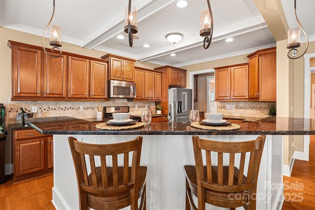 6422 Northern Red Oak Dr, Mint Hill, NC 28227 - kitchen featuring appliances with stainless steel finishes, brown cabinets, light wood-type flooring, decorative backsplash, and a kitchen bar