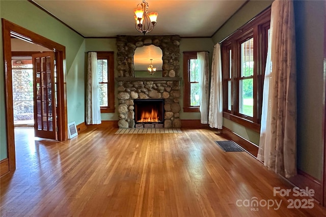 4320 Pisgah Dr, Canton, NC 28716 - unfurnished living room with a chandelier, baseboards, wood finished floors, a stone fireplace, and ornamental molding