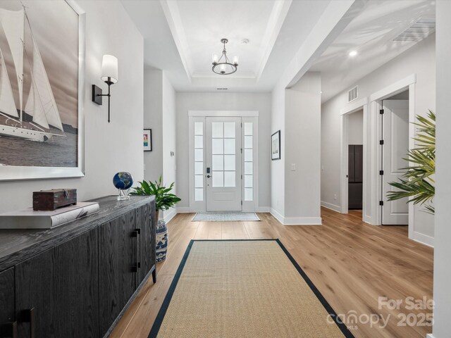 6020 Waldorf Ave, Monroe, NC 28110 - entrance foyer featuring light wood-style flooring, a tray ceiling, a chandelier, and ornamental molding