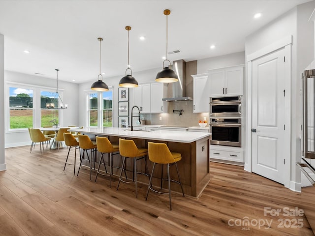 6020 Waldorf Ave, Monroe, NC 28110 - kitchen with wall chimney exhaust hood, stainless steel double oven, hardwood / wood-style flooring, light countertops, and recessed lighting