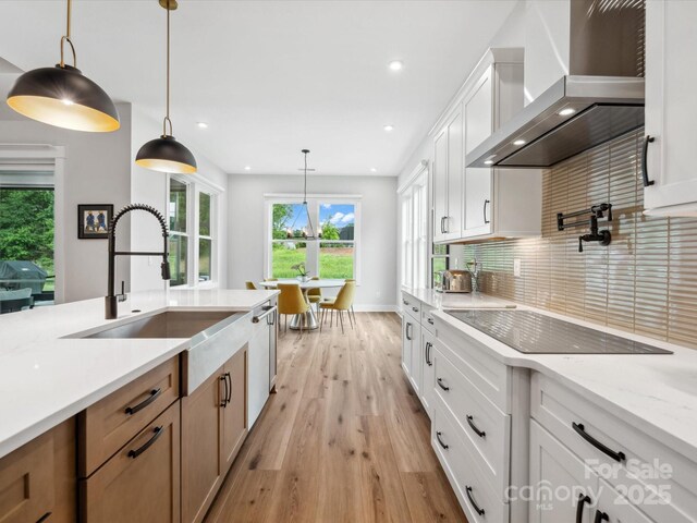 6020 Waldorf Ave, Monroe, NC 28110 - kitchen with wall chimney range hood, light wood finished floors, recessed lighting, tasteful backsplash, and decorative light fixtures
