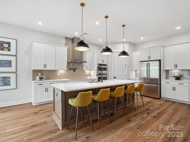 6020 Waldorf Ave, Monroe, NC 28110 - kitchen featuring appliances with stainless steel finishes, wall chimney exhaust hood, tasteful backsplash, light countertops, and light wood-style floors