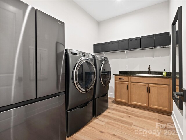 6020 Waldorf Ave, Monroe, NC 28110 - washroom with independent washer and dryer, bar with sink, light wood-style floors, and cabinet space