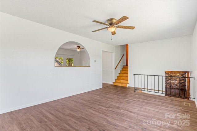 4980 Murray Rd, Winston Salem, NC 27106 - spare room featuring ceiling fan, wood finished floors, stairway, baseboards, and arched walkways