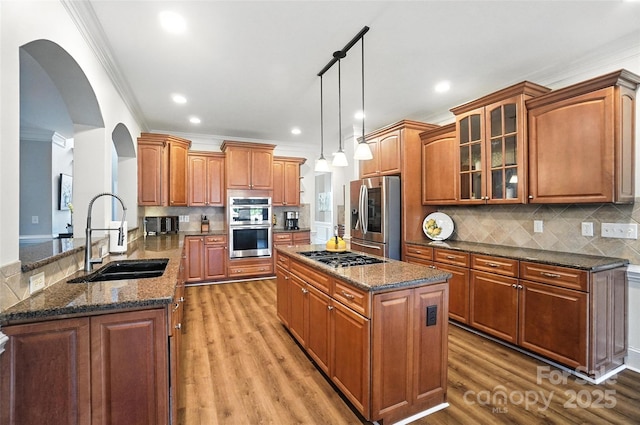 5916 Four Wood Dr, Matthews, NC 28104 - kitchen featuring appliances with stainless steel finishes, crown molding, arched walkways, a kitchen island, and glass insert cabinets