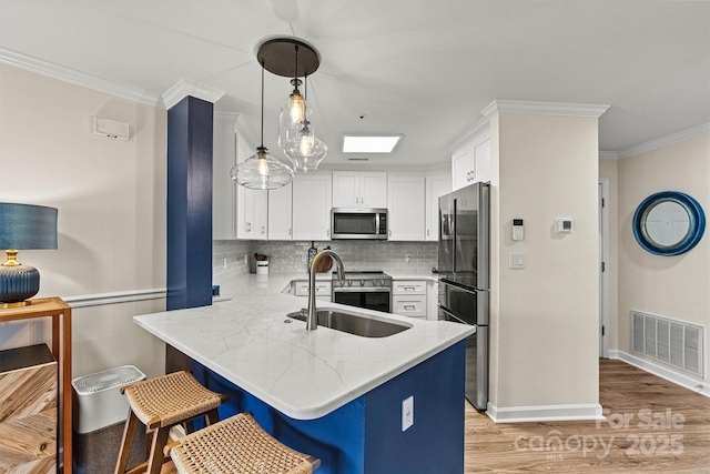 1038 SW Dr, Davidson, NC 28036 - kitchen with stainless steel appliances, a peninsula, crown molding, white cabinets, and tasteful backsplash