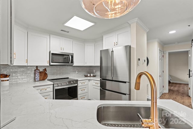 1038 SW Dr, Davidson, NC 28036 - kitchen featuring stainless steel appliances, decorative backsplash, light stone countertops, white cabinetry, and crown molding