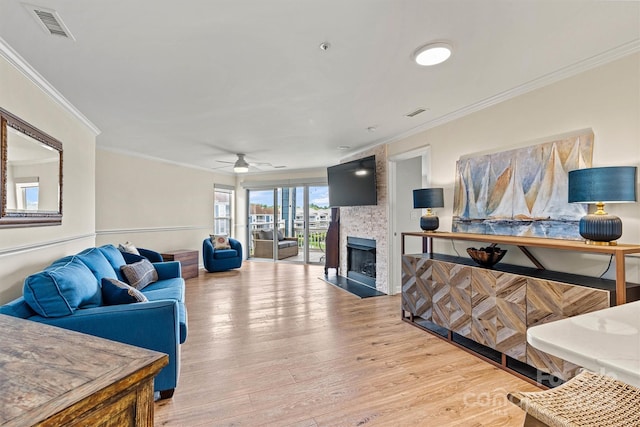 1038 SW Dr, Davidson, NC 28036 - living room featuring a large fireplace, light wood finished floors, crown molding, and a ceiling fan