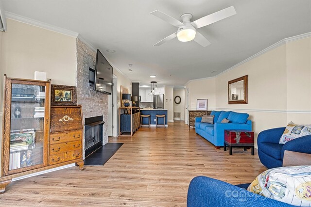 1038 SW Dr, Davidson, NC 28036 - living area featuring crown molding, light wood-style flooring, a large fireplace, and a ceiling fan