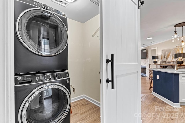 1038 SW Dr, Davidson, NC 28036 - washroom featuring stacked washing machine and dryer, light wood-style flooring, and crown molding