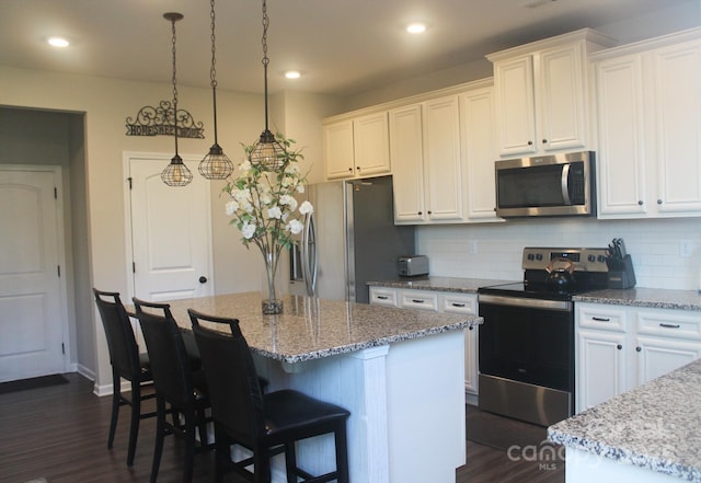 858 Oak Manor Dr SE, Concord, NC 28025 - kitchen with stainless steel appliances, dark wood-type flooring, backsplash, white cabinets, and a center island