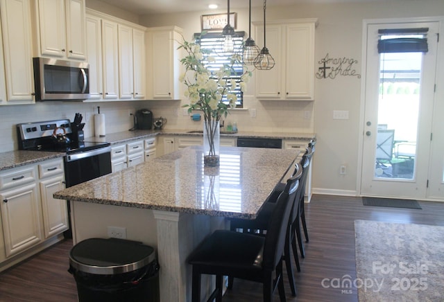 858 Oak Manor Dr SE, Concord, NC 28025 - kitchen with stainless steel appliances, dark wood-style floors, a breakfast bar area, tasteful backsplash, and a kitchen island