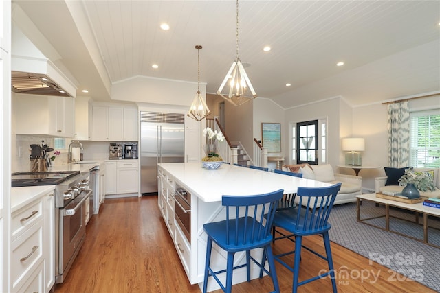 4126 Tyndale Ave, Charlotte, NC 28210 - kitchen featuring premium appliances, vaulted ceiling, recessed lighting, light wood-style floors, and a kitchen breakfast bar