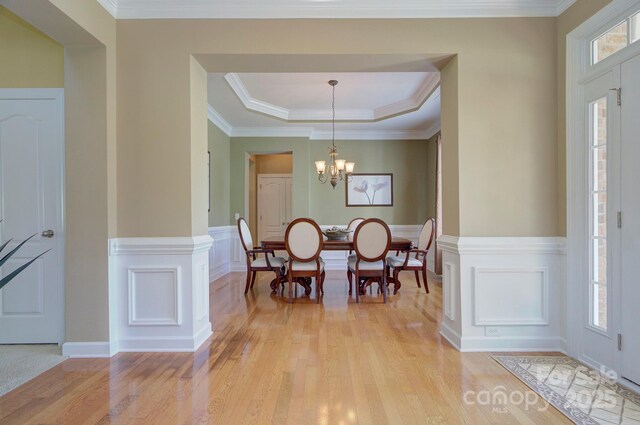 604 Palmerston Ln, Waxhaw, NC 28173 - dining room with light wood-style flooring, a chandelier, wainscoting, a raised ceiling, and ornamental molding
