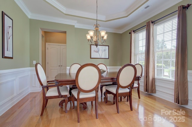604 Palmerston Ln, Waxhaw, NC 28173 - dining space featuring light wood-style floors, a chandelier, wainscoting, a raised ceiling, and ornamental molding