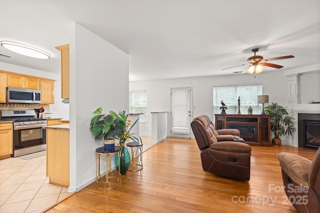 9236 Clifton Meadow Dr, Matthews, NC 28105 - living area with light wood-style flooring, ceiling fan, and a fireplace