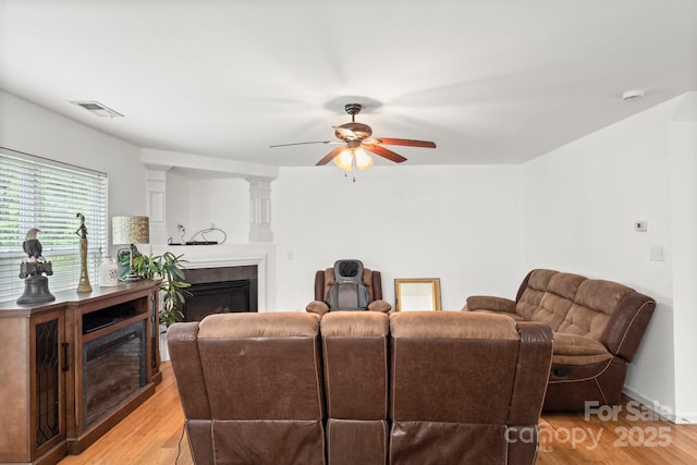 9236 Clifton Meadow Dr, Matthews, NC 28105 - living area with a glass covered fireplace, a ceiling fan, and light wood-type flooring