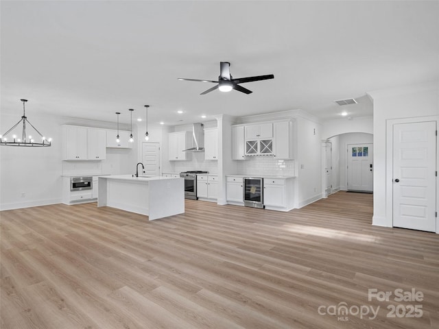 8303 Adrian Ct, Charlotte, NC 28270 - unfurnished living room with beverage cooler, arched walkways, light wood-style flooring, a chandelier, and ceiling fan