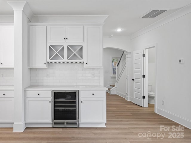 8303 Adrian Ct, Charlotte, NC 28270 - indoor dry bar featuring wine cooler, arched walkways, ornamental molding, decorative backsplash, and baseboards