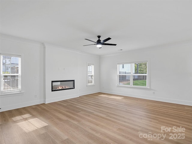 8303 Adrian Ct, Charlotte, NC 28270 - unfurnished living room featuring plenty of natural light, light wood-type flooring, crown molding, a glass covered fireplace, and baseboards