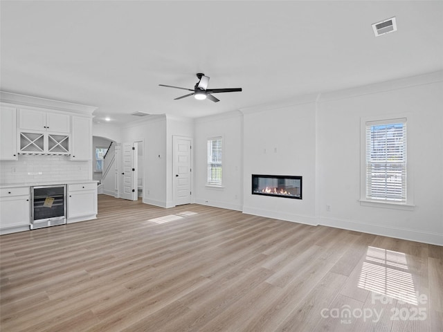 8303 Adrian Ct, Charlotte, NC 28270 - unfurnished living room with beverage cooler, ceiling fan, baseboards, a glass covered fireplace, and light wood finished floors