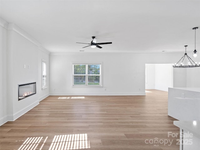 8303 Adrian Ct, Charlotte, NC 28270 - unfurnished living room with a chandelier, a ceiling fan, light wood-style floors, a glass covered fireplace, and ornamental molding