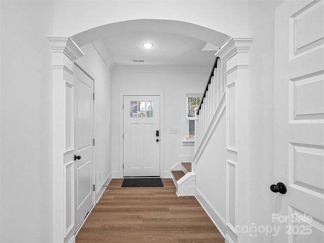 8303 Adrian Ct, Charlotte, NC 28270 - foyer entrance with arched walkways, wood finished floors, decorative columns, stairs, and crown molding
