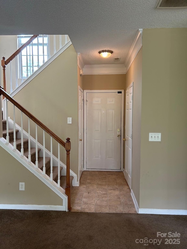 8125 Weeping Fig Ln, Charlotte, NC 28215 - carpeted entrance foyer with stairway, crown molding, a textured ceiling, and tile patterned flooring