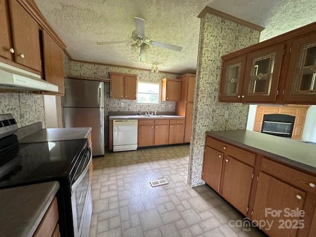 5587 Doe Ct, Morganton, NC 28655 - kitchen with appliances with stainless steel finishes, under cabinet range hood, brick patterned floors, wallpapered walls, and ceiling fan