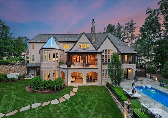 8500 Longview Club Dr, Waxhaw, NC 28173 - back of house at dusk featuring a balcony, stucco siding, a patio area, and a standing seam roof