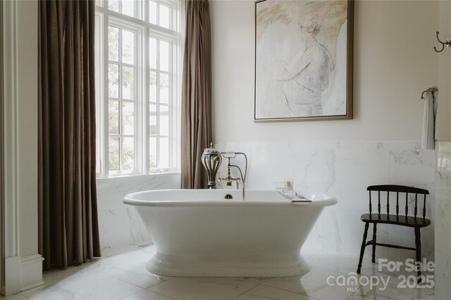 8500 Longview Club Dr, Waxhaw, NC 28173 - full bathroom featuring healthy amount of natural light, tile walls, a soaking tub, wainscoting, and marble finish floors