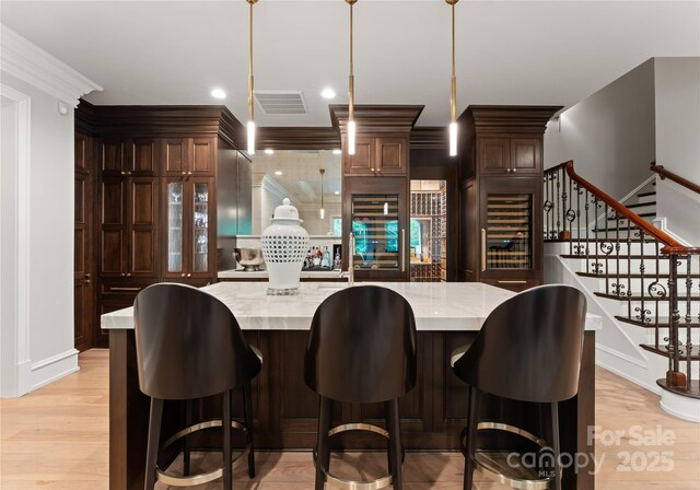 8500 Longview Club Dr, Waxhaw, NC 28173 - kitchen featuring wine cooler, light wood-style flooring, hanging light fixtures, crown molding, and a spacious island