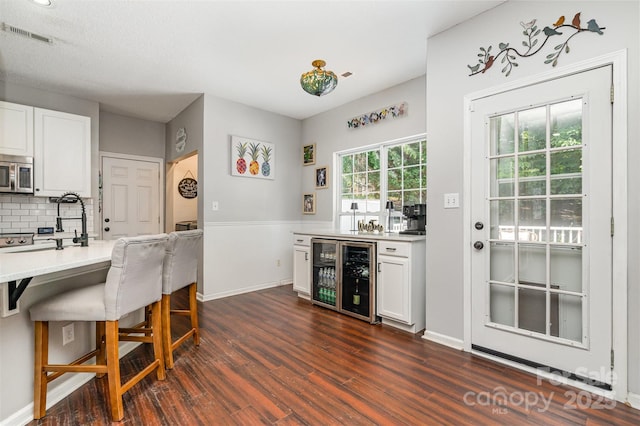 108 Shade Tree Cir, Fort Mill, SC 29715 - kitchen with wine cooler, stainless steel microwave, dark wood-style flooring, backsplash, and white cabinetry