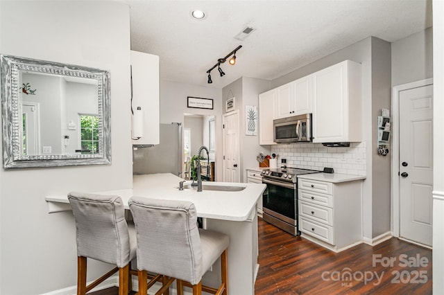 108 Shade Tree Cir, Fort Mill, SC 29715 - kitchen featuring appliances with stainless steel finishes, white cabinetry, light countertops, a kitchen breakfast bar, and tasteful backsplash