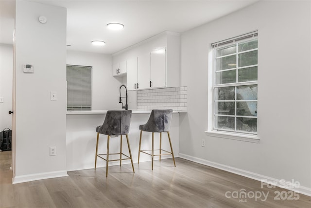 3941 Briarhill Dr, Charlotte, NC 28215 - kitchen with a kitchen breakfast bar, wood finished floors, white cabinetry, light countertops, and plenty of natural light