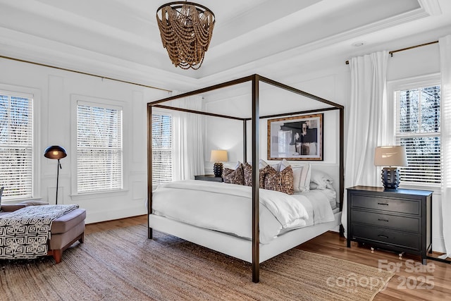 394 Stonecliff Ln, Clover, SC 29710 - bedroom featuring a chandelier, wood finished floors, a decorative wall, multiple windows, and a tray ceiling