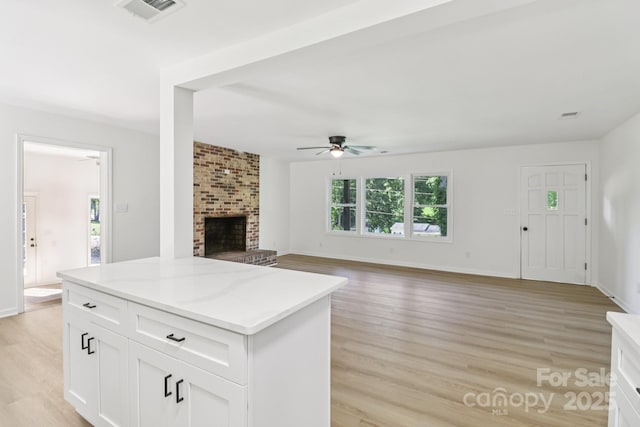 848 Ike Lynch Rd, Dallas, NC 28034 - kitchen with ceiling fan, a brick fireplace, light wood-style flooring, and white cabinets