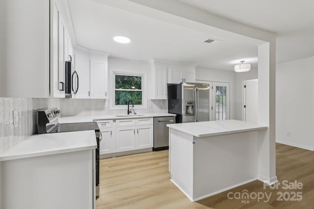 848 Ike Lynch Rd, Dallas, NC 28034 - kitchen featuring appliances with stainless steel finishes, light wood finished floors, tasteful backsplash, and white cabinetry