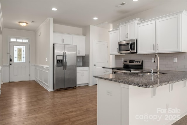 10410 Bradstreet Commons Way, Charlotte, NC 28215 - kitchen with appliances with stainless steel finishes, a peninsula, wood finished floors, tasteful backsplash, and crown molding