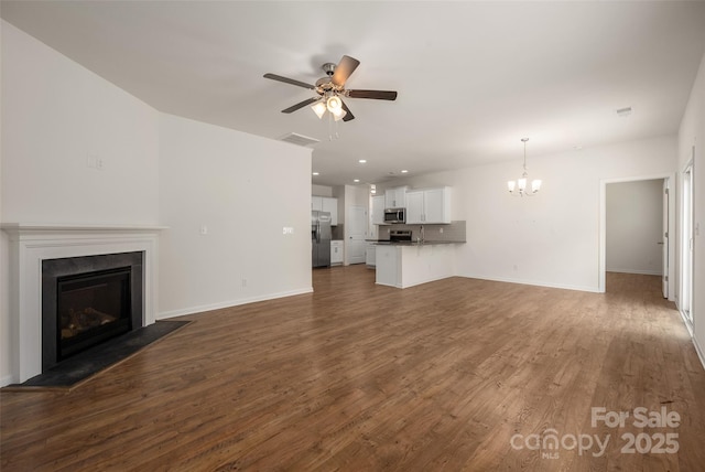 10410 Bradstreet Commons Way, Charlotte, NC 28215 - unfurnished living room featuring a glass covered fireplace, a chandelier, a ceiling fan, dark wood-style flooring, and recessed lighting