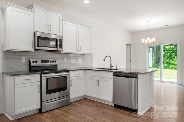 10410 Bradstreet Commons Way, Charlotte, NC 28215 - kitchen with stainless steel appliances, a peninsula, a chandelier, white cabinetry, and wood finished floors